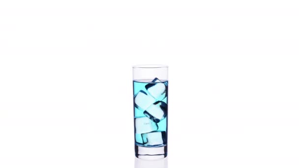 青いカクテルとアイスキューブが白い背景の上にストップモーションで充填し 空にするガラス — ストック動画