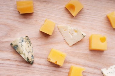 Bir kesme tahtası üzerinde çedar peyniri ve mavi rokfor parçaları.