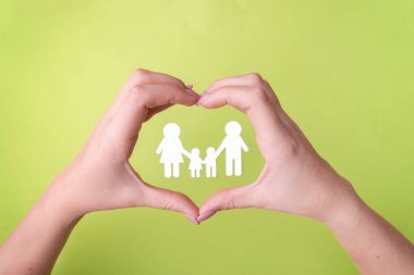 Sağlığı koruyan dost bir ailenin sembolü, beyaz kağıt bir aile. Yeşil arka plan ve orkide çiçekleri. Yukarıdan görünüm yazıt için bir yer vardır. Yeşil arka plan.