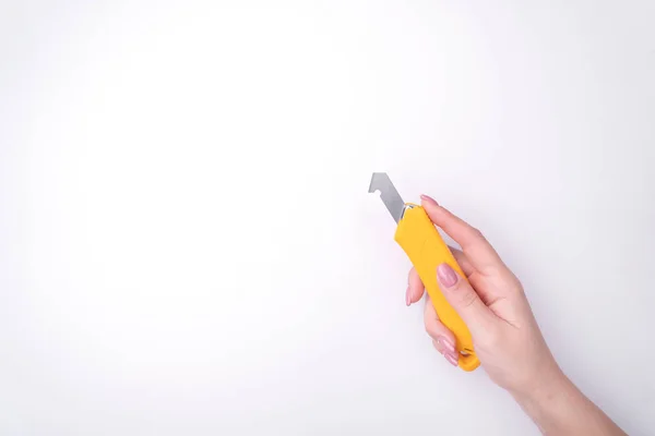 La mano de la mujer de moda con una manicura suave sostiene una herramienta. Trabajo seguro, lugar para una inscripción. Vista desde arriba. Fondo blanco, sombra contrastante . — Foto de Stock