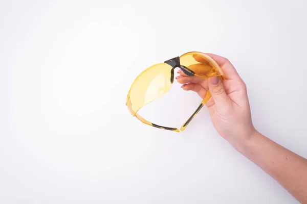 Fashion woman's hand with a gentle manicure holds a tool. Safe work, place for an inscription. View from above. White background, contrasting shadow. — Stock Photo, Image