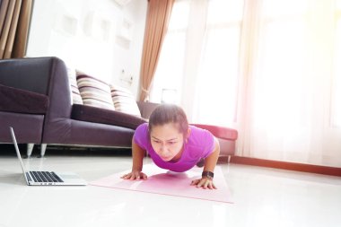 Asyalı kadınlar egzersiz egzersiz evde, yukarı itin dizüstü bilgisayar kullanan ile yapıyor