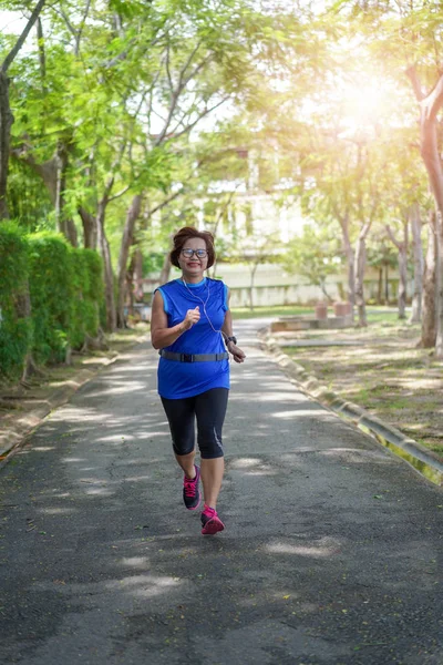 スポーツの活動の概念を運動公園で実行している上級アジアの女性の幸せなジョギング — ストック写真