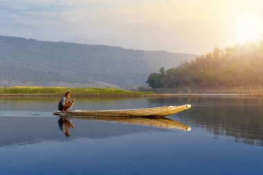 Nakhon Ratchasima, Tayland - 6 Ocak: balıkçılık oturan yaşlı adam ahşap tekne Tay adam sabahı 6 Ocak 2019 Tayland Nakhon Ratchasima şehirde sırasında gölde bir tekne kürek çekmeye.