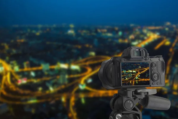 Câmera digital sobre tripé em edifícios cityscape à noite, Cidade — Fotografia de Stock