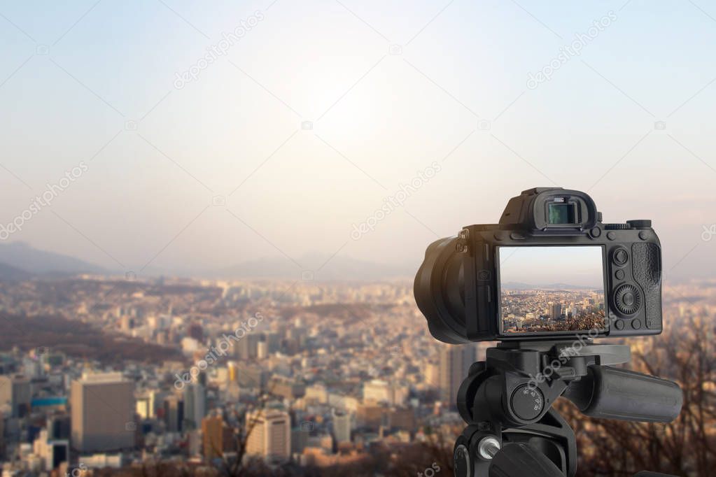 Digital camera over tripod on cityscape with blue sky at sunset 