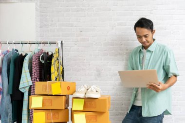 Asya adam tuğla duvarda dizüstü bilgisayar çalışıyor standı