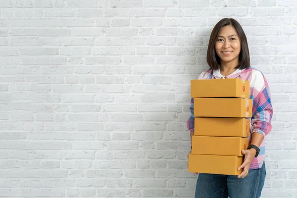 Азіатські жінки несуть коричневі посилки або картонні коробки на цегляній стіні — стокове фото