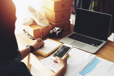 Ev ofis masasında not kağıdı ile akıllı pone kullanarak kadın el