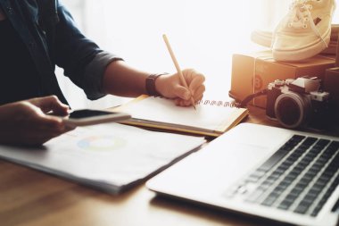 Ev ofis masasında not kağıdı ile akıllı pone kullanarak kadın el