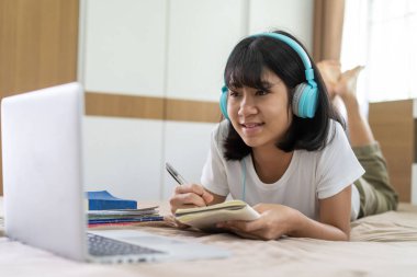 Asyalı kız internette ödev okuyor evde ders veriyor, sosyal uzaklık online eğitim fikri