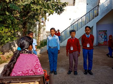 Katni Bölgesi, Madhya Pradesh, Hindistan - 07 Ocak 2020: Hintli ilkokul öğrencisi sınıfın önünde bayan öğretmenin önünde duruyor.