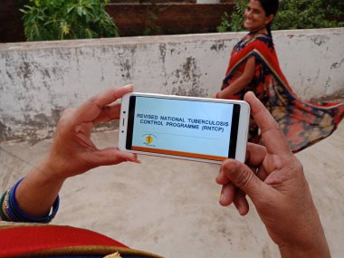 Katni Bölgesi, Madhya Pradesh, Hindistan - 23 Mayıs 2020: Açık arkaplanda Hintli bir kadın tarafından akıllı telefon ekranında hükümet planının gözden geçirilmiş hali.