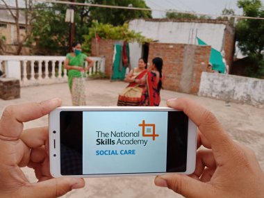 DISTRICT KATNI, INDIA - 23 Mayıs 2020: Ulusal beceri akademisi sosyal hizmet şeması olan akıllı telefonu ekranda tutan kadın. Hindistan hükümeti iktidar partisi bu politikaya fakir insanlara yardım etmek için başladı.