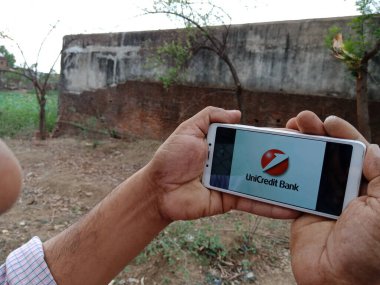 DISTRICT KATNI, INDIA - HAZİRAN 02, 2020: UniCredit Finansal Hizmetler Şirketi logosunu ekranda gösteren akıllı bir telefon tutan Hintli adam, köy halkı için modern bankacılık eğitimi kavramı.