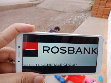DISTRICT KATNI, INDIA - HAZİRAN 02, 2020: Köylüler için modern bankacılık eğitim kavramı olan Rosbank Business logosunu ekranda gösteren akıllı bir telefon tutan Hintli kadın.