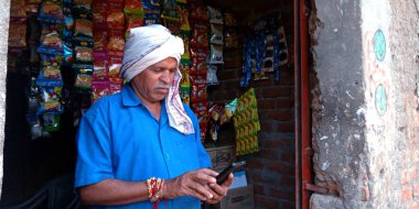 DİSTRİK KATNI, INDIA - 20 AĞUSTOS 2019: Asyalı geleneksel insanlar için akıllı telefon teknolojisi kullanan bir Hintli köy esnaf dijital öğrenim kavramı.
