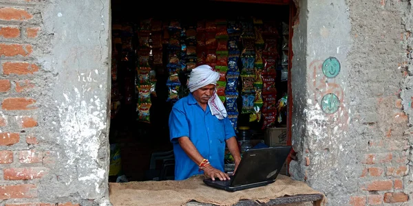 DISTRICT KATNI, INDIA - 20 AĞUSTOS 2019: Asyalıların dijital öğrenme kavramı için dizüstü bilgisayar teknolojisi kullanan Hintli yaşlı bir dükkan sahibi.