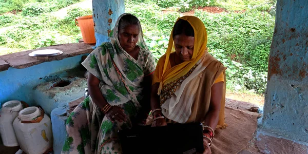 DISTRICT KATNI, INDIA - 16 Ağustos 2019: 2 Hintli köyü fakir evlerinde dizüstü bilgisayar kullanan iki yetişkin kadın. Köylü teknolojisi öğrenme kavramı.