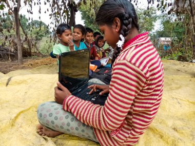 DISTRICT KATNI, INDIA - HAZİRAN 01, 2020: Bir grup çocukla bilgisayar işleten Hint köyü kızı, dijital teknoloji farkındalığı kavramı.