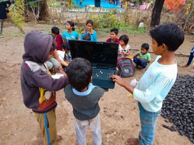 DISTRICT KATNI, INDIA - HAZİRAN 01, 2020: Üç Hint köyü çocuğu bir grup çocukla dizüstü bilgisayar kullanıyor, dijital teknoloji farkındalığı kavramı.