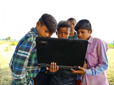 DISTRICT KATNI, INDIA - HAZİRAN 01, 2020: Açık ve doğal arka planda dizüstü bilgisayar teknolojisini birlikte öğrenen bir grup çocuk.