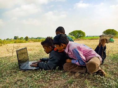 DISTRICT KATNI, INDIA - HAZİRAN 01, 2020: Açık alanda dizüstü bilgisayar teknolojisini birlikte öğrenen bir grup fakir çocuk.