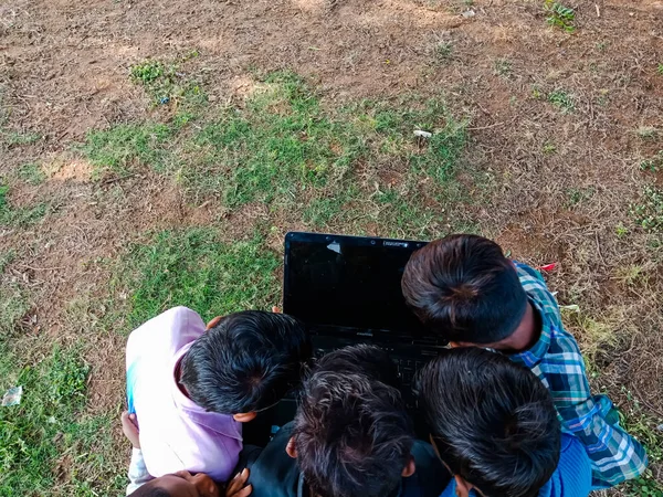 DISTRICT KATNI, INDIA - HAZİRAN 01, 2020: Açık ve doğal arka planda dizüstü bilgisayar teknolojisini birlikte öğrenen bir grup çocuk.