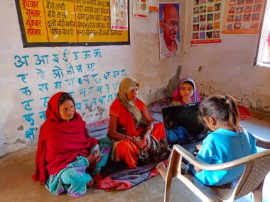 DISTRICT KATNI, INDIA - HAZİRAN 01, 2020: Hintli bir köy kızı Anganwadi Hükümet Merkezi 'ndeki fakir kadına dizüstü bilgisayar teknolojisi hakkında ders veriyor.