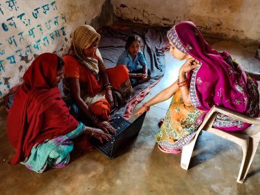DISTRICT KATNI, INDIA - HAZİRAN 01, 2020: Bir Hint köyü Anganwadi bayan öğretmeni bir grup yoksul kadına dizüstü bilgisayar teknolojisi hakkında ders veriyor.