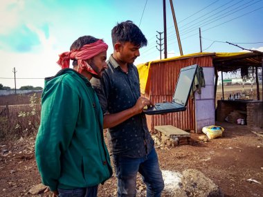DISTRICT KATNI, INDIA - HAZİRAN 01, 2020: İki Hint köylü açık alanda endüstriyel alanda dizüstü bilgisayar öğreniyor.