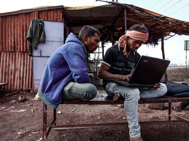 DISTRICT KATNI, INDIA - HAZİRAN 01, 2020: Açık alanda dizüstü bilgisayar teknolojisini birlikte öğrenen iki Hintli erkek.