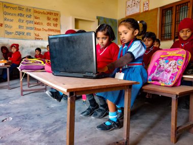 DİSTRİK KATNI, INDIA - 13 HAZİRAN 2020: Hintli ilkokul öğrencileri sınıf sıralarında dizüstü bilgisayar teknolojisini birlikte öğreniyorlar.