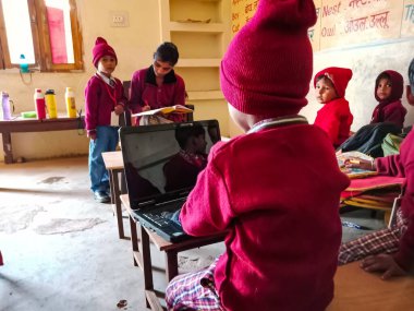 DİSTRİK KATNI, INDIA - 13 HAZİRAN 2020: Hintli bir ilkokul çocuğu tek başına sınıftaki banklarda laptop teknolojisini öğreniyor.