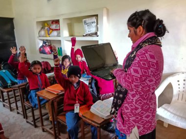 DİSTRİK KATNI, INDIA - 13 HAZİRAN 2020: Hintli ilkokul öğretmeni sınıftaki öğrenciye laptop teknolojisi hakkında eğitim veriyor.