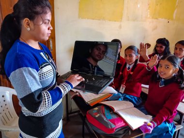 DİSTRİK KATNI, INDIA - 13 HAZİRAN 2020: Hintli ilkokul öğretmeni sınıftaki öğrenciye laptop teknolojisi hakkında eğitim veriyor.