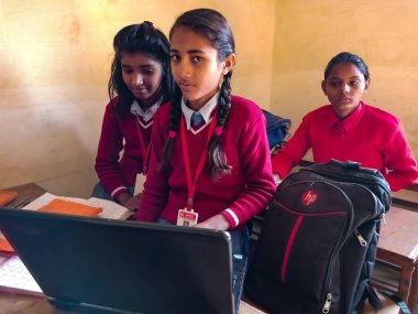 DİSTRİK KATNI, INDIA - 13 HAZİRAN 2020: Hintli ilkokul öğrencileri sınıf sıralarında dizüstü bilgisayar teknolojisini birlikte öğreniyorlar.