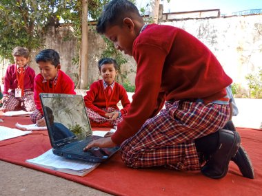 DİSTRİK KATNI, INDIA - 13 HAZİRAN 2020: Hindistan ilköğretim okulu erkek öğrencileri açık mekanlarda dizüstü bilgisayar teknolojisini öğreniyorlar.