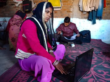 DISTRICT KATNI, INDIA - 25 HAZİRAN 2020: Evinde dizüstü bilgisayar teknolojisi kullanan bir Hintli köy kadını, dijital farkındalık kavramı.