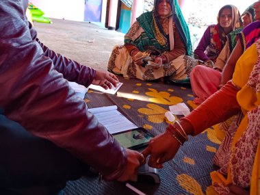 DISTRICT KATNI, INDIA - 25 HAZİRAN 2020: Bir Hintli banka memuru kredi geri ödemesi toplamak için dijital ped üzerinde parmak izi aldığı için kadın parmağını tutuyor.