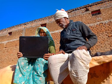 DISTRICT KATNI, INDIA - 25 HAZİRAN 2020: Mavi gökyüzü arka planında dizüstü bilgisayar teknolojisini birlikte öğrenen Hintli bir çift.