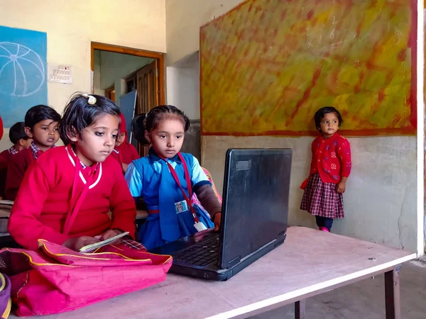 DİSTRİK KATNI, INDIA - 13 HAZİRAN 2020: İki Hintli ilkokul öğrencisi sınıf sıralarında dizüstü bilgisayar teknolojisini birlikte öğreniyorlar.