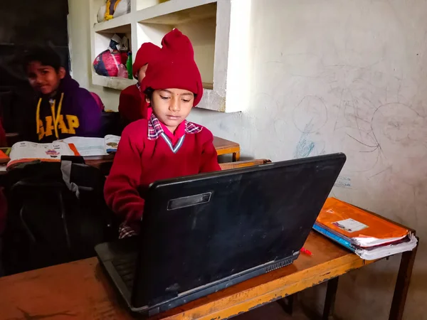 DİSTRİK KATNI, INDIA - 13 HAZİRAN 2020: Hindistan ilköğretim okulunda sınıf banklarında dizüstü bilgisayar kullanan kız öğrenci.