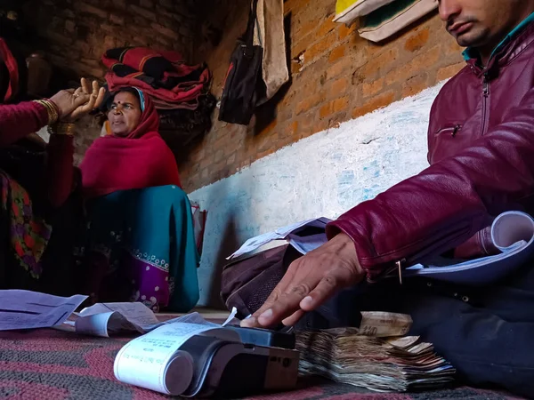DISTRICT KATNI, INDIA - 25 HAZİRAN 2020: Hintli bir mikro-finans memuru dijital i ped makinesinde küçük bir kadın grubundan kredi geri ödemesi almak için parmak izi veriyor.
