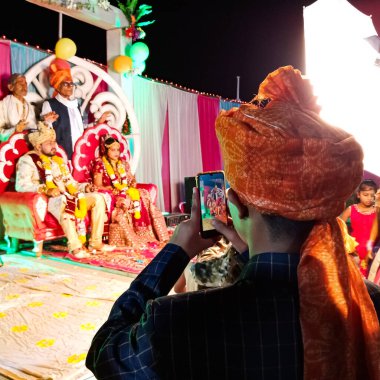 DISTRICT KATNI, INDIA - 23 Şubat 2020: Hintli geleneksel bir adam Hintli bir çiftin güzel evlilik töreni sırasında akıllı telefon kamerasından fotoğraf çekiyor.