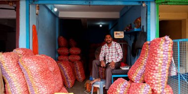 DISTRICT KATNI, INDIA - 07 Ağustos 2019: Hint çiftçilerinin tarım ürünleri pazarında soğan stoklarında oturan Asya köyü erkek mağazası sahibi.