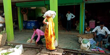 DISTRICT KATNI, INDIA - 07 Ağustos 2019: Asyalı bir köylü kadın bakkal Hint çiftçilerinin tarım ürünleri pazarında kafasında sebze çuvalları taşıyordu.