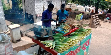 DISTRICT JABALPUR, INDIA - 17 Ağustos 2019: Asyalı esnaf Narmada Nehri Caddesi pazarında turist için mısır satıyor.