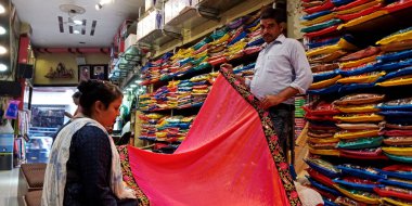 DISTRICT KATNI, INDIA - 18 EPTEMBER 2019: Hintli bir satıcı Hint festivali pazarında geleneksel sari 'yi kadın müşterilere sunuyor.