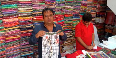 DISTRICT KATNI, INDIA - 18 Eylül 2019: Hindistan festivali pazarında çocukları tanıtan Hintli satıcılar giyim mağazasında satış teklif ediyorlar.